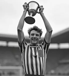 Glücklicher junger Sportler, der nach einem Sportsieg eine Trophäe hochhält.